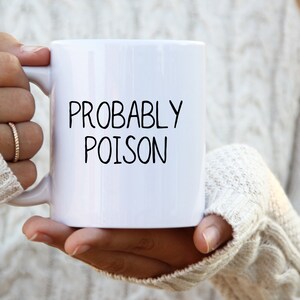May include: White ceramic mug with black text that reads "PROBABLY POISON".