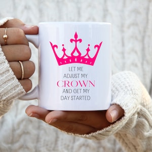 May include: White ceramic mug with a pink crown graphic and the text "Let me adjust my crown and get my day started".