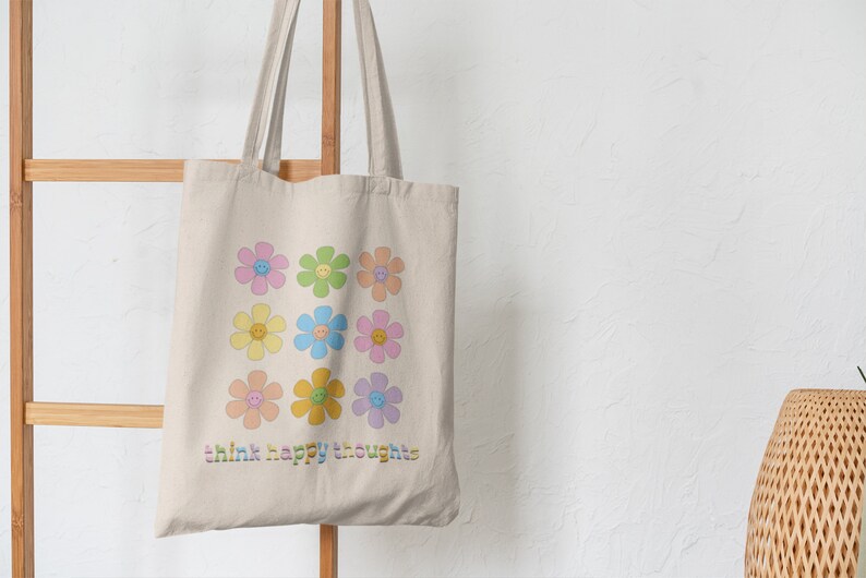 May include: A beige tote bag with a design of colorful flowers with smiley faces. The text "think happy thoughts" is printed on the bag.