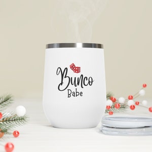 Puede incluir: Un vaso de acero inoxidable blanco con un dise&ntilde;o en negro y rojo que dice "Bunco Babe".