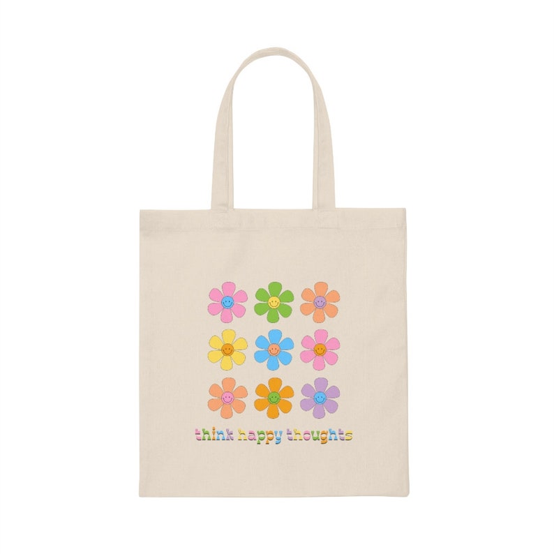 May include: A beige tote bag with a design of nine colorful flowers with smiley faces. The text "think happy thoughts" is printed in rainbow colors at the bottom of the bag.