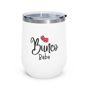 Puede incluir: Un vaso de acero inoxidable blanco con un dise&ntilde;o en blanco y negro que dice "Bunco Babe" y un gr&aacute;fico de dados rojo.