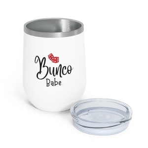 Puede incluir: Un vaso de acero inoxidable blanco con una tapa plateada. El vaso tiene un gr&aacute;fico de dados rojos y el texto "Bunco Babe" en letra cursiva negra.
