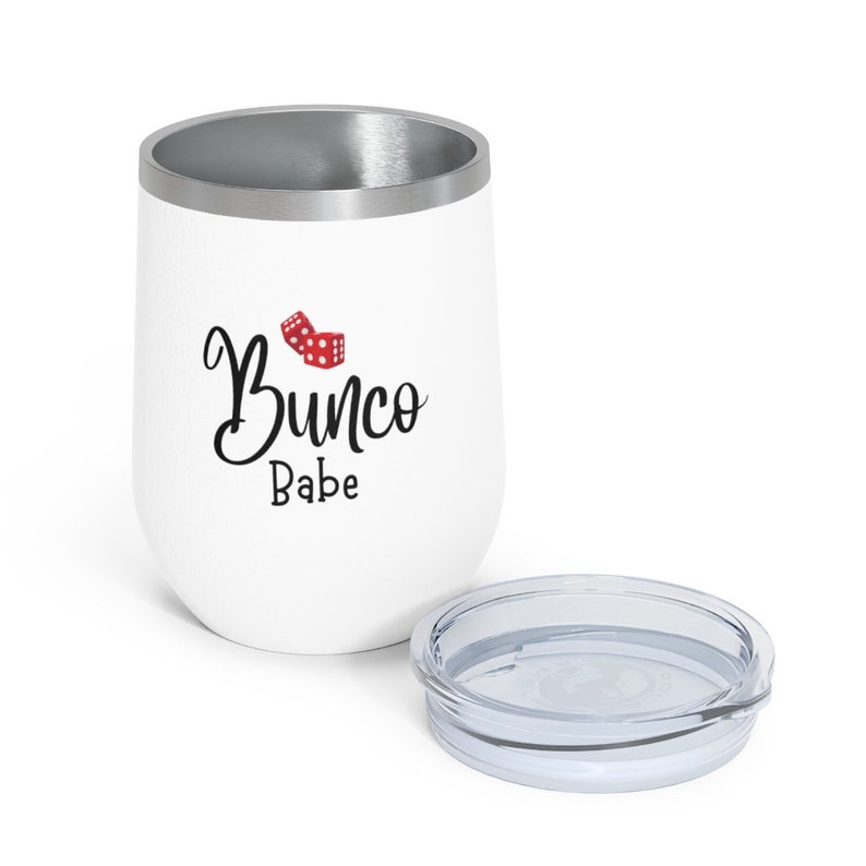 Puede incluir: Un vaso de acero inoxidable blanco con una tapa plateada. El vaso tiene un gr&aacute;fico de dados rojos y el texto "Bunco Babe" en letra cursiva negra.