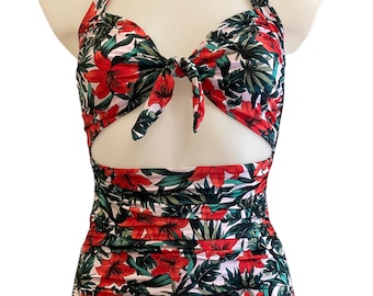 May include: A red and green floral print swimsuit with a halter top and a cut-out design. The swimsuit has a high-waisted bottom and a ruched design.