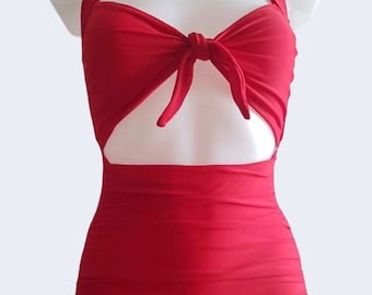 May include: A red one-piece swimsuit with a halter top and a cut-out detail at the chest. The top ties in a bow at the center.