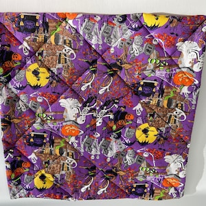 May include: Purple quilted fabric with a Halloween theme. The fabric features a variety of Halloween icons, including ghosts, pumpkins, bats, witches, and skeletons. The fabric is perfect for crafting projects, such as pillows, blankets, and bags.
