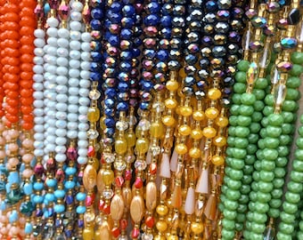 Puede incluir: Una variedad de collares de cuentas de colores, incluyendo naranja, blanco, azul, verde y dorado. Los collares están hechos de diferentes tipos de cuentas, incluyendo vidrio, cristal y plástico.