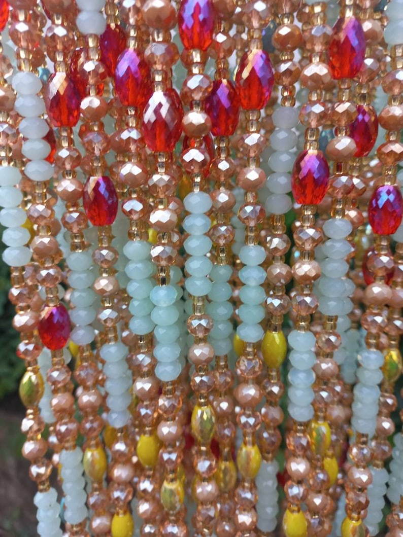 Puede incluir: Un collar de cuentas de m&uacute;ltiples hilos con una mezcla de cuentas de color verde claro, melocot&oacute;n, amarillo y rojo. Las cuentas est&aacute;n dispuestas en un patr&oacute;n en cascada.