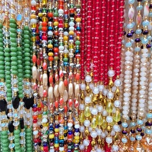 Puede incluir: Una variedad de collares de cuentas coloridas con diferentes texturas y patrones. Los collares est&aacute;n hechos de cuentas de vidrio, cuentas de madera y cuentas de metal. Algunos de los collares tienen un acabado dorado.