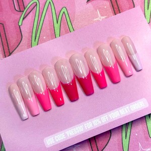 May include: A set of ten long, coffin-shaped press-on nails. Each nail features a gradient design, transitioning from a clear base to shades of pink and red at the tips. The nails are arranged on a pink card with text.