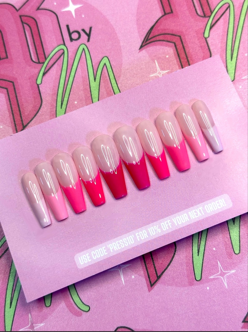 May include: A set of ten long, coffin-shaped press-on nails. Each nail features a gradient design, transitioning from a clear base to shades of pink and red at the tips. The nails are arranged on a pink card with text.