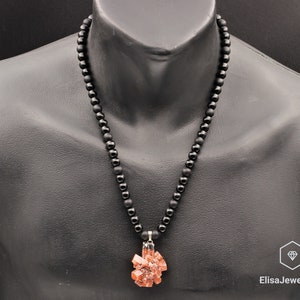 May include: A black beaded necklace with a pendant made of a cluster of orange-brown crystals.