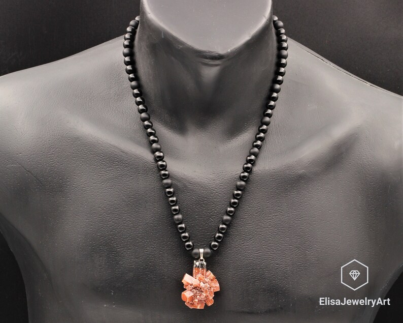 May include: A black beaded necklace with a pendant made of a cluster of orange-brown crystals.