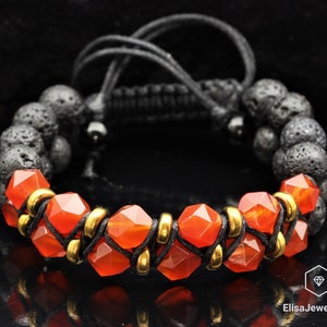 May include: A bracelet featuring orange carnelian beads, gold spacers, and black lava rock beads. The bracelet is secured with black cord.