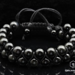 May include: Black beaded bracelet with a double row of round beads and a black cord closure.