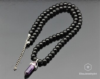 May include: A black onyx beaded necklace with a silver clasp and a purple amethyst point pendant.