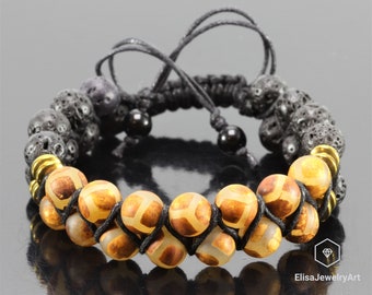 May include: A black cord bracelet with brown and gold agate beads and black lava rock beads. The bracelet is tied with a macrame knot.