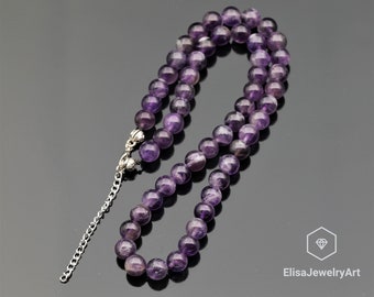 May include: A purple amethyst gemstone necklace with a silver chain and clasp. The necklace is made of round beads and is approximately 18 inches long.