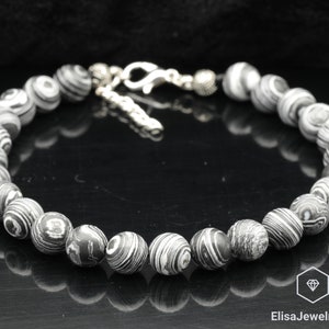 May include: Black and white patterned bracelet with silver clasp and beads.