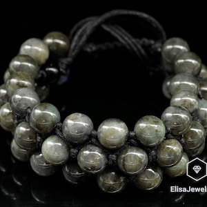 May include: A double-strand bracelet made with dark green labradorite beads and black cord. The bracelet is tied with a knot and has a tassel.