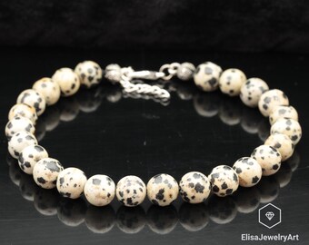 May include: A black and white dalmatian jasper beaded bracelet with a silver clasp.
