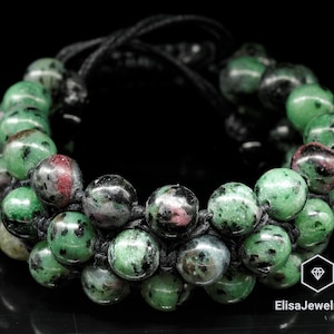 May include: A green and black gemstone bracelet with a black cord. The bracelet is made of round beads and has a double row of beads.
