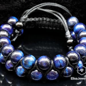 May include: A blue tiger's eye beaded bracelet with black cord and a macrame knot closure. The bracelet is made with multiple strands of beads.