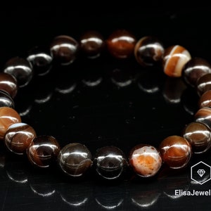 May include: A bracelet made of brown, black, and white agate beads. The beads are round and have a polished finish.