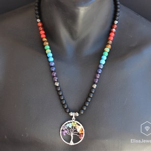 May include: A black beaded necklace with a silver tree of life pendant. The pendant is adorned with colourful gemstones, including red, orange, yellow, green, blue, indigo, and violet.