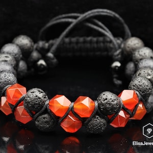 May include: A black lava rock and carnelian gemstone bracelet with a black cord. The bracelet is made with alternating black lava rock beads and orange carnelian beads.