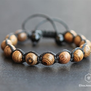 May include: A black cord bracelet with brown wood beads. The beads have a striped pattern.