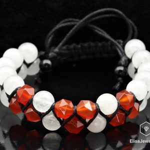 May include: A bracelet made with white and red gemstone beads, with a black cord closure. The bracelet is made with two rows of beads, one row of white beads and one row of red beads.