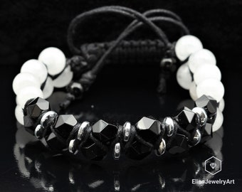 May include: Black and white beaded bracelet with black cord and silver accents. The bracelet features black faceted beads and white round beads.