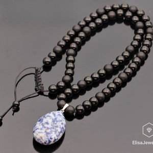 May include: A black beaded necklace with a blue and white gemstone pendant. The necklace is made of matte black beads and has a simple adjustable cord closure.