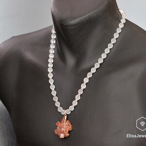May include: A white frosted bead necklace with a brown crystal pendant. The necklace is on a mannequin.