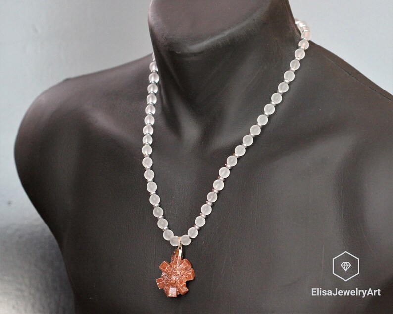 May include: A white frosted bead necklace with a brown crystal pendant. The necklace is on a mannequin.