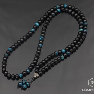 May include: Black and blue beaded necklace with a silver clasp. The beads are round and have a smooth, polished finish.
