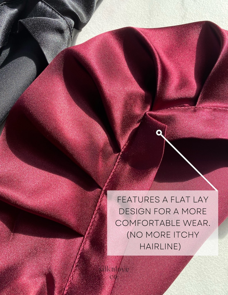 May include: A close-up of a burgundy satin fabric with a flat lay design. The fabric is smooth and has a subtle sheen. The text "FEATURES A FLAT LAY DESIGN FOR A MORE COMFORTABLE WEAR. (NO MORE ITCHY HAIRLINE)" is visible in the image.