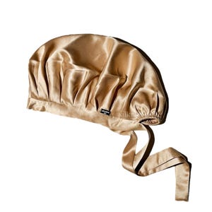 May include: A gold satin sleep cap with a tie closure. The cap is made of 100% mulberry silk.