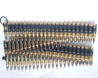 May include: A long chain of gold-colored bullets linked together with black elastic bands. The bullets are arranged in a staggered pattern, with the tips of the bullets pointing in opposite directions.