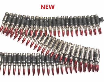 May include: A silver and black bullet belt with red tips. The belt is made of metal and has a black rubber backing. NEW is written in red letters above the belt.
