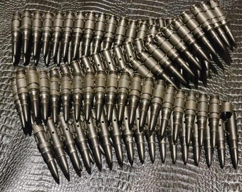 May include: A collection of metallic, dark gray bullets linked together in a belt formation. The bullets have a pointed tip and a cylindrical body. The arrangement is displayed against a textured, dark surface.