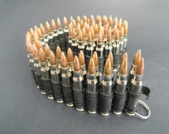 May include: A silver and copper bullet belt with black elastic bands. The belt is made of a series of bullets connected together with the elastic bands. The belt has a silver ring on the end.