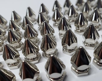 Puede incluir: Una gran cantidad de tachuelas de metal de forma piramidal de color plateado. Las tachuelas tienen una base hexagonal y una punta puntiaguda.