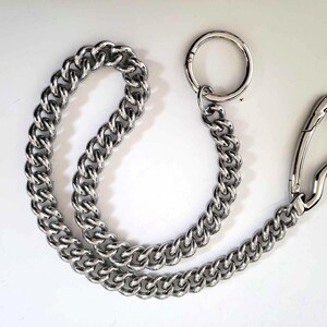 May include: A silver-colored chain with a large, rounded link design. The chain is connected to a large circular ring and a spring-loaded clasp. The chain is made of a shiny, metallic material.