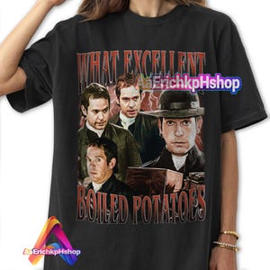 Puede incluir: Camiseta negra con un estampado gráfico de cuatro hombres con ropa de época. El texto "What Excellent Boiled Potatoes" está impreso en rojo en la camiseta.