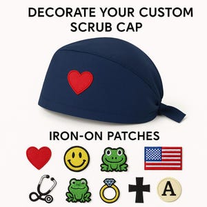 May include: Navy blue scrub cap with a red heart patch. The image also shows various iron-on patches, including a smiley face, frog, American flag, stethoscope, ring, cross, and the letter A. Text reads "DECORATE YOUR CUSTOM SCRUB CAP" and "IRON-ON PATCHES."