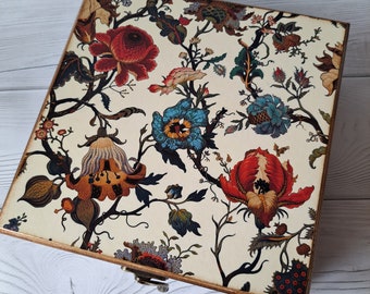 May include: A wooden box with a hinged lid. The lid is decorated with a floral pattern in shades of red, blue, yellow, and green. The box is a great way to store small items.