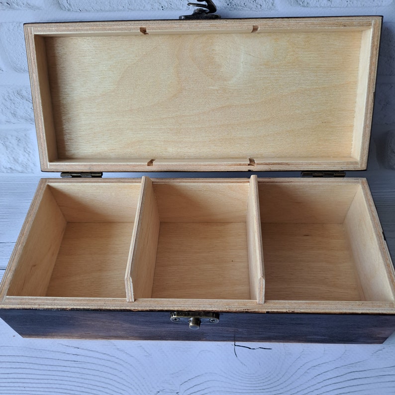 May include: A wooden box with a hinged lid and a brass latch. The box has three compartments inside.